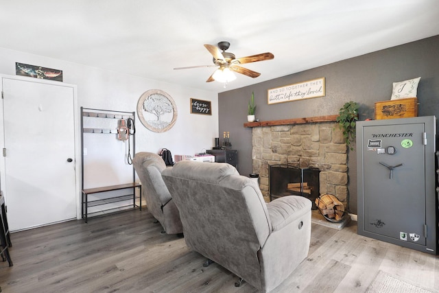 living area featuring light wood finished floors, a fireplace, and a ceiling fan