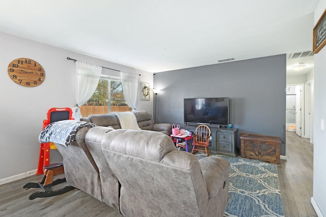 living room featuring wood finished floors, visible vents, and baseboards