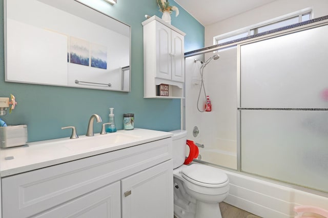 bathroom featuring enclosed tub / shower combo, wood finished floors, vanity, and toilet