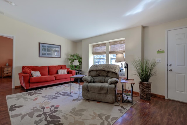 living area with baseboards, visible vents, vaulted ceiling, and dark wood-type flooring