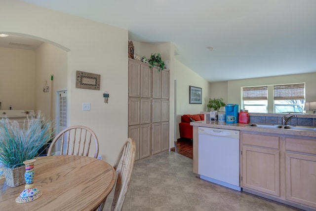 kitchen with arched walkways, light brown cabinetry, white dishwasher, and light countertops