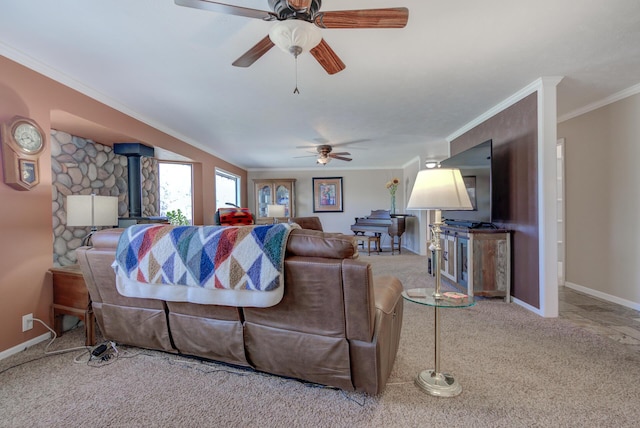 living room featuring ornamental molding, a ceiling fan, a wood stove, light carpet, and baseboards