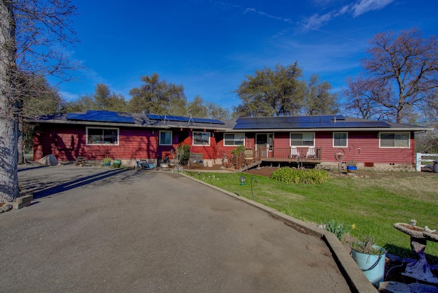 ranch-style house with aphalt driveway, solar panels, crawl space, a wooden deck, and a front lawn