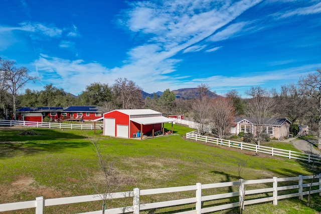 view of yard with an outbuilding, driveway, and a rural view