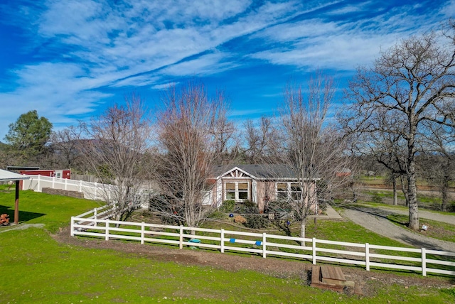 view of front of property featuring a fenced front yard, a rural view, and a front lawn