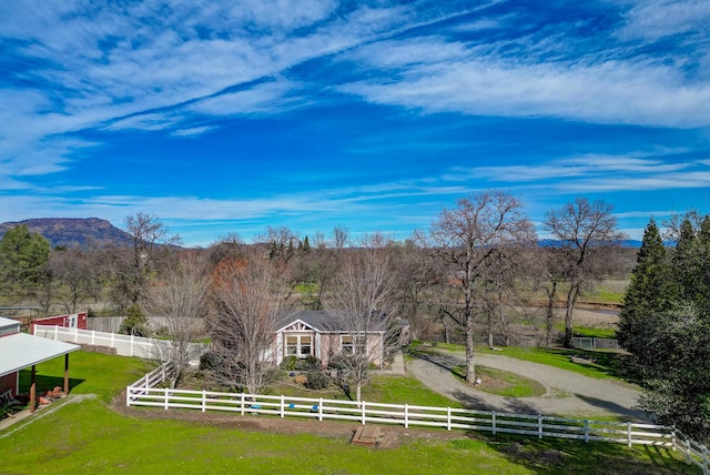 exterior space with a fenced front yard, a mountain view, a front lawn, and a rural view