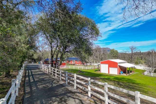 exterior space with a garage, an outbuilding, a rural view, and fence