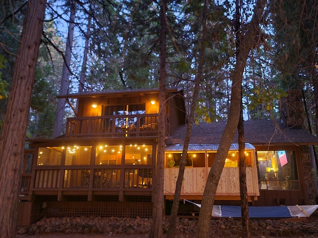 back of property featuring a sunroom and a balcony