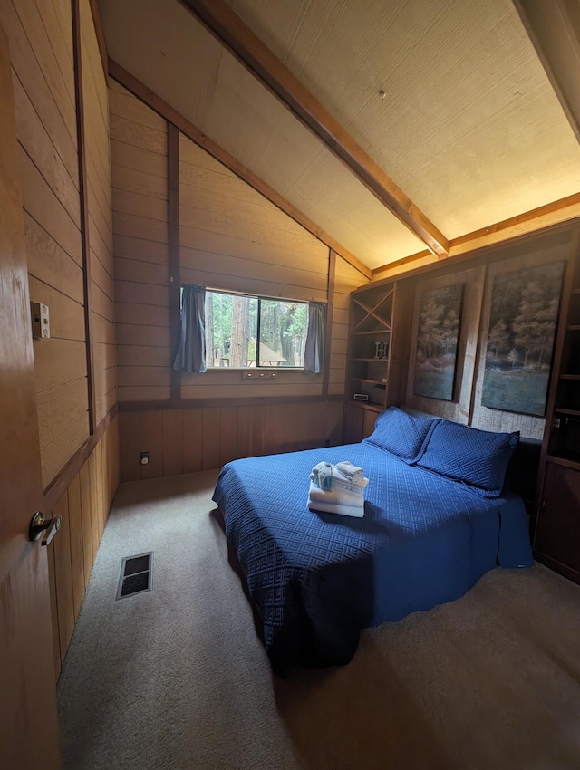 carpeted bedroom featuring vaulted ceiling with beams, wooden walls, and visible vents