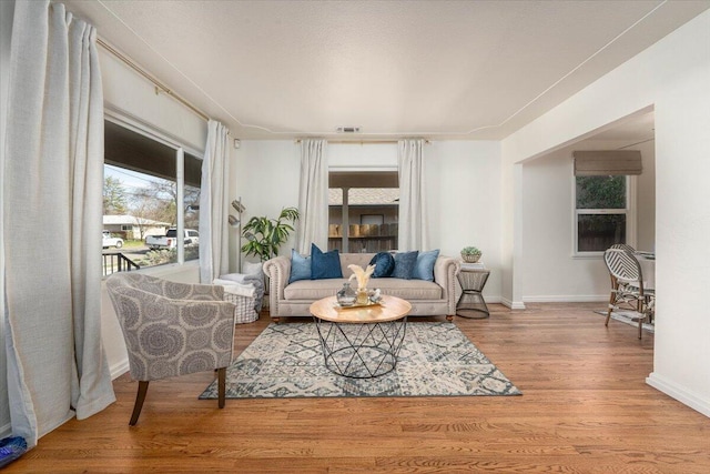 living area featuring baseboards, visible vents, and wood finished floors