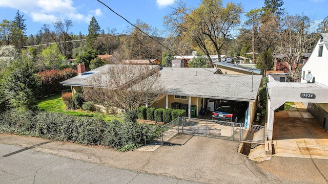 ranch-style home with an attached carport, fence, roof with shingles, driveway, and a gate