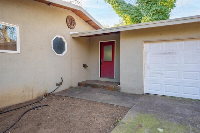 doorway to property with a garage and stucco siding