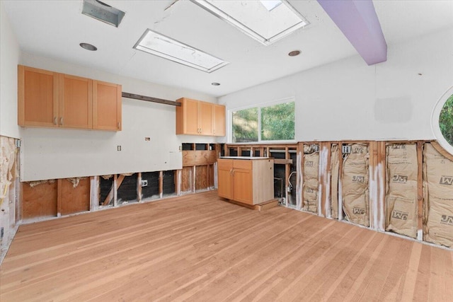 kitchen featuring light wood finished floors, light brown cabinets, and beamed ceiling