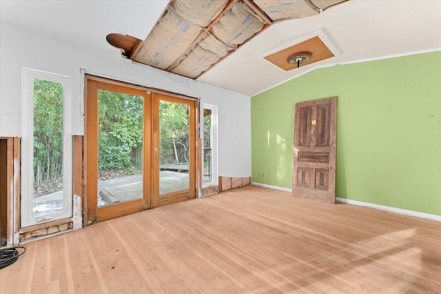 empty room featuring vaulted ceiling, french doors, baseboards, and light wood-style floors