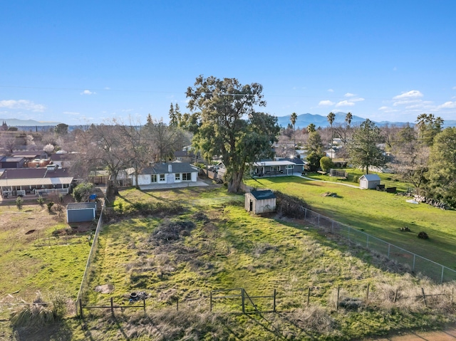 view of yard featuring a residential view, an outbuilding, fence, a shed, and a mountain view