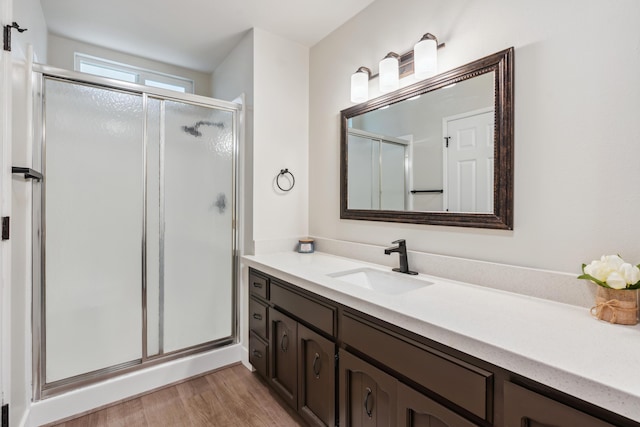 bathroom featuring wood finished floors, a shower stall, and vanity