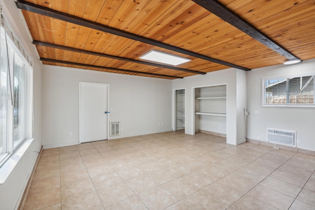 unfurnished bedroom with light tile patterned floors, beam ceiling, a wall mounted air conditioner, and wooden ceiling