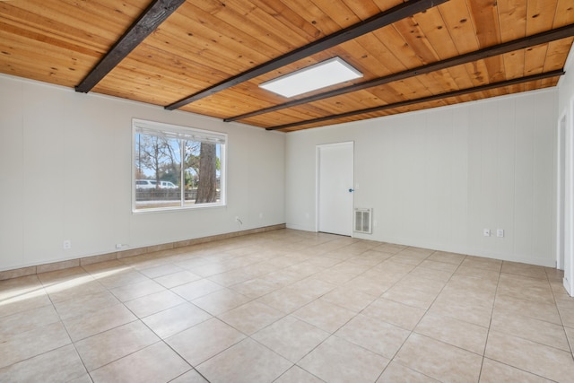 empty room with a skylight, light tile patterned floors, visible vents, wood ceiling, and beamed ceiling