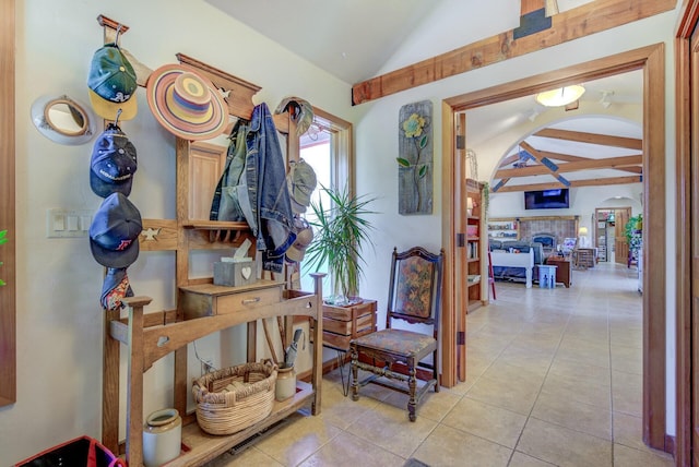 hallway featuring lofted ceiling with beams, light tile patterned flooring, and arched walkways