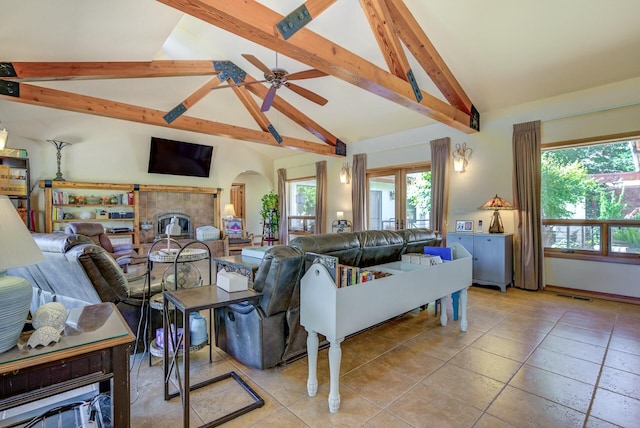 living area featuring visible vents, arched walkways, a tile fireplace, high vaulted ceiling, and beam ceiling