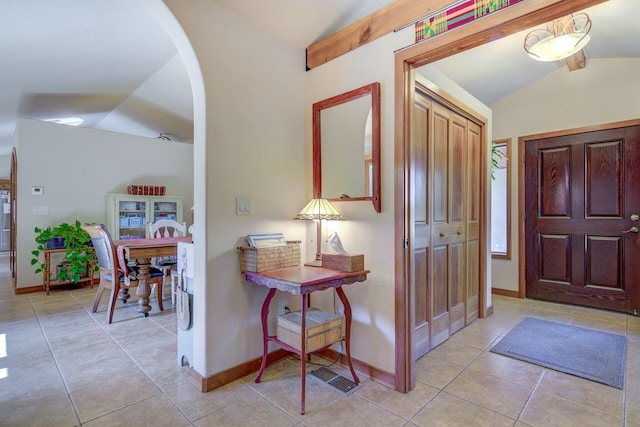 foyer with lofted ceiling, baseboards, arched walkways, and light tile patterned flooring