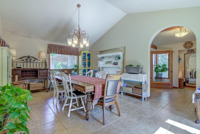 dining area with high vaulted ceiling, arched walkways, light tile patterned floors, and an inviting chandelier