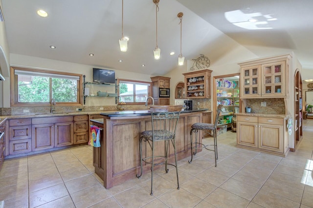 kitchen featuring a center island with sink, glass insert cabinets, and open shelves