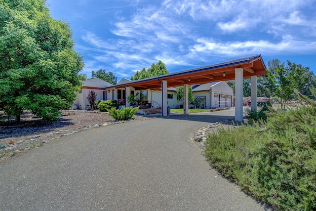 view of home's community featuring aphalt driveway, a carport, and an outbuilding