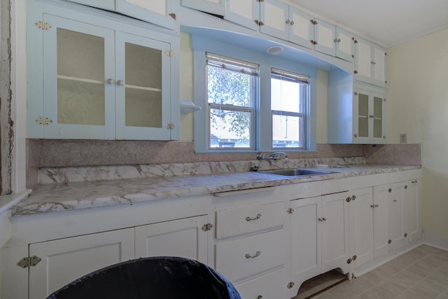 kitchen with glass insert cabinets, light countertops, a sink, and white cabinetry