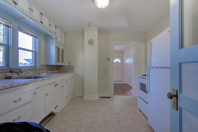 kitchen featuring light countertops, white appliances, a sink, and white cabinetry