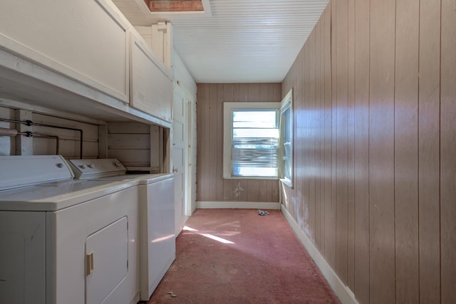 washroom with cabinet space, wooden walls, baseboards, and separate washer and dryer