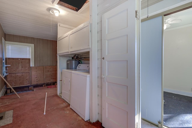 clothes washing area featuring cabinet space, independent washer and dryer, wood walls, and water heater