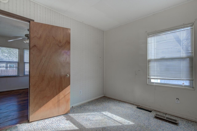 spare room featuring visible vents, ceiling fan, baseboards, and wallpapered walls