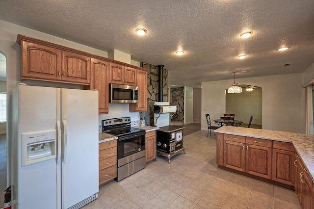 kitchen featuring a textured ceiling, appliances with stainless steel finishes, brown cabinetry, and light stone counters