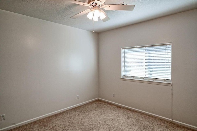 carpeted spare room featuring a textured ceiling, a ceiling fan, and baseboards