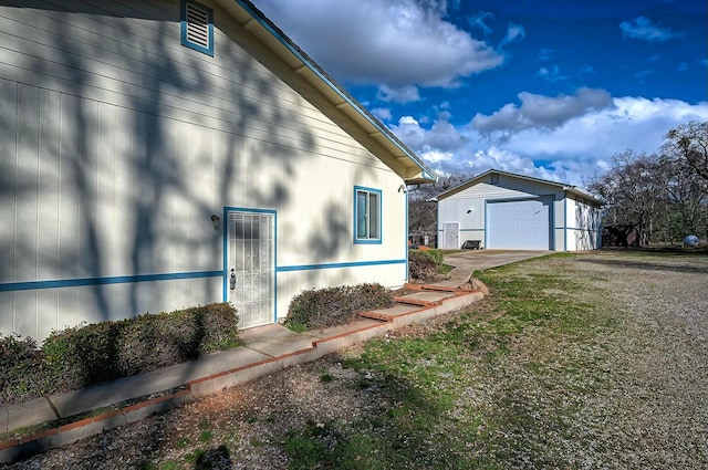 view of side of home featuring a detached garage, a lawn, and an outdoor structure