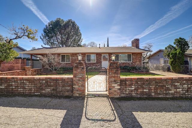 single story home featuring a fenced front yard, a gate, brick siding, and a chimney