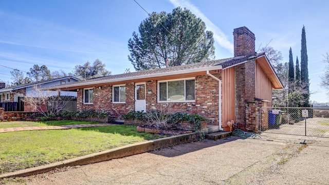 single story home featuring brick siding, a chimney, a front lawn, and fence