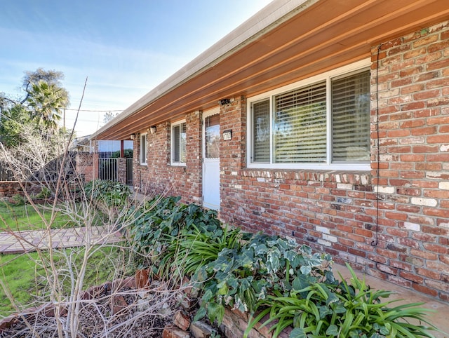 exterior space featuring brick siding and fence