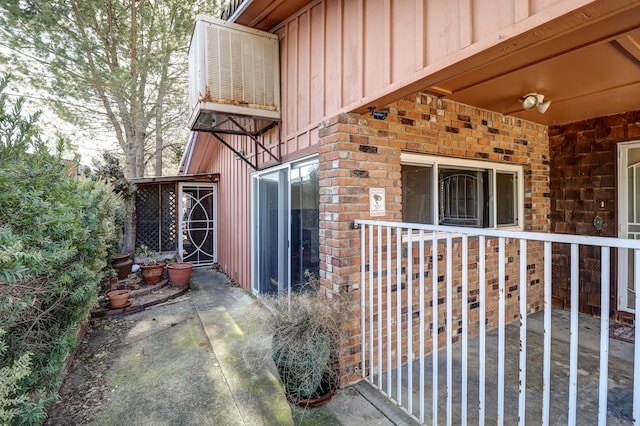 property entrance featuring board and batten siding, brick siding, a patio, and central AC