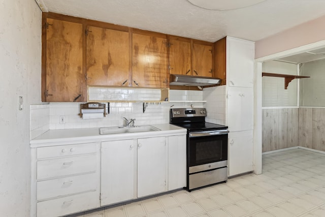 kitchen featuring light floors, light countertops, a sink, under cabinet range hood, and stainless steel electric range