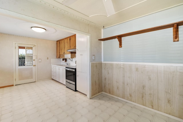 kitchen featuring under cabinet range hood, a sink, light countertops, light floors, and stainless steel range with electric stovetop