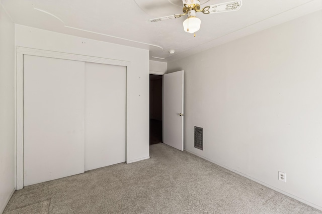 unfurnished bedroom featuring light carpet, ceiling fan, visible vents, and a closet