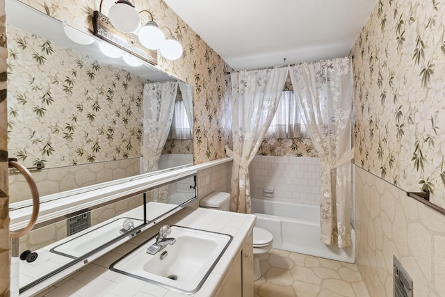 bathroom featuring shower / tub combo with curtain, tile walls, toilet, vanity, and wallpapered walls