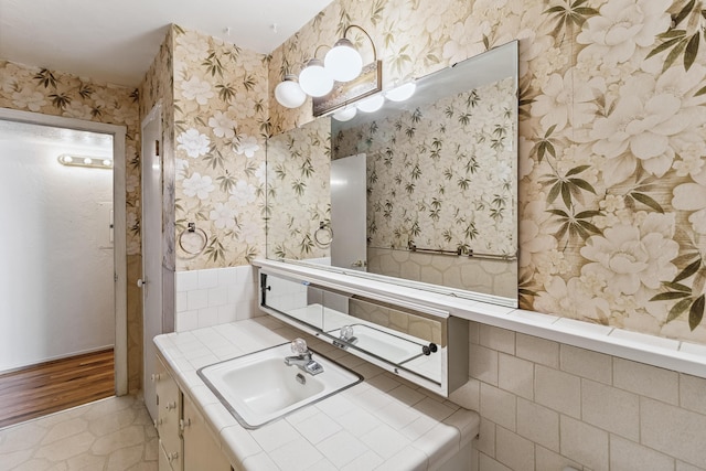 bathroom with wallpapered walls and vanity