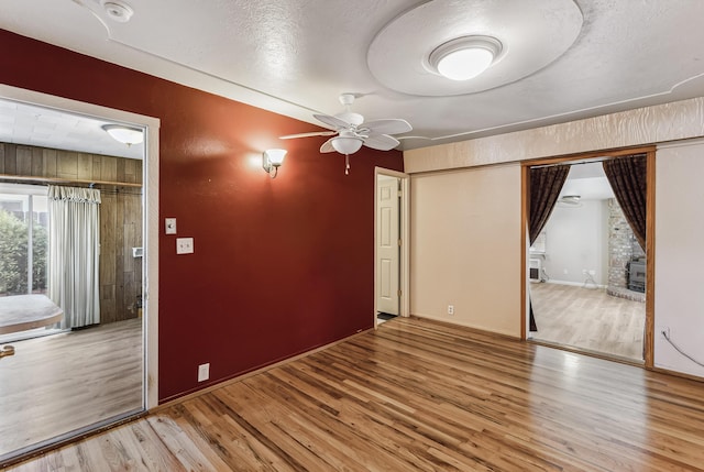 spare room with ceiling fan, a textured ceiling, baseboards, and wood finished floors