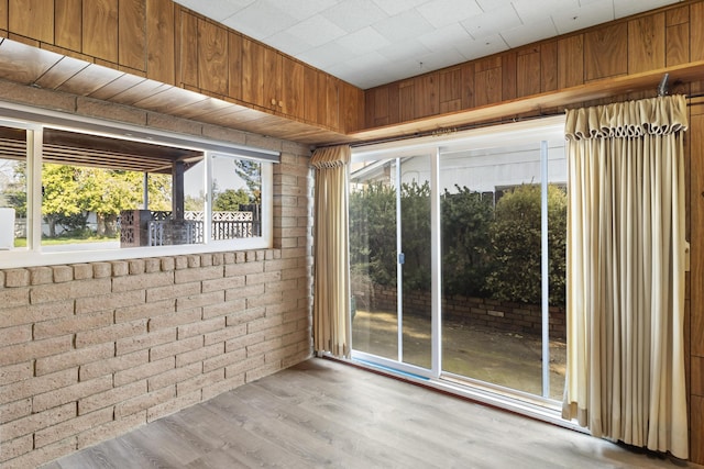 doorway to outside with brick wall and light wood-type flooring