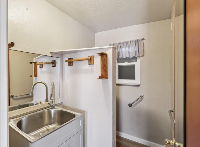 kitchen featuring a textured ceiling, a sink, and baseboards