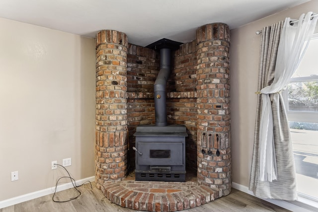 room details with wood finished floors, a wood stove, and baseboards