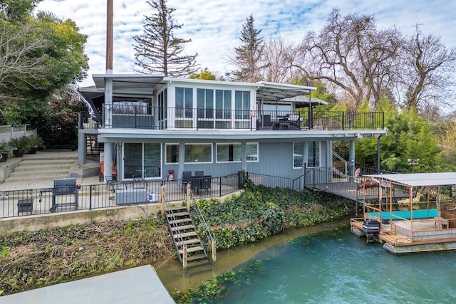 back of house with a sunroom, a water view, and stairs